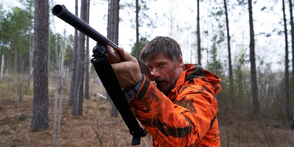 Nikolaj Coster-Waldau holds up a hunting rifle while playing Rayburn in The Silencing.